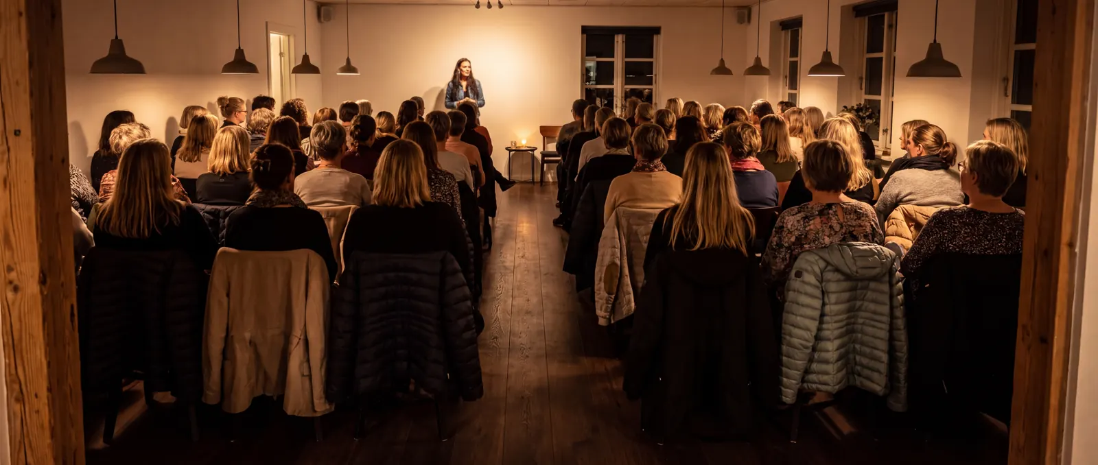 Fuldt hus til en klarsynsaften — publikum på stolerækker foran Rikke Rostholm